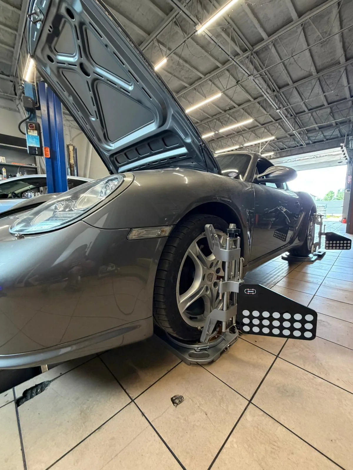 Porsche Cayman starszej generacji podczas pomiaru geometrii kół – obejma z targetem FCAR na przednim kole